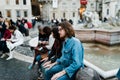 Roma, Italy, November 1, 2015: A group of young tourists sitting at an urban fountain