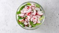 Romaine lettuce salad with fresh sliced radishes close-up in a glass bowl, flat lay with copy space