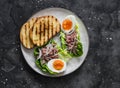 Romaine salad boat with canned tuna and boiled egg - delicious breakfast, tapas, snack on a dark background, top view