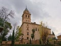 Low angle view on Church of Santa Maria de Alhambra,Granada, Spain, surrounded by trees on a cloudy day Royalty Free Stock Photo