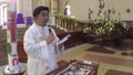 Roman Catholic priest saying homily in front of church altar during baptism rites