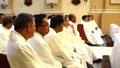 Roman Catholic priests seated chatting listening to homily during congregation mass