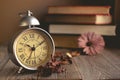 Roman Numeral in Vintage Alarm Clock and Stack of Book Background