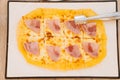 Roman pizza with cheese and ham is taken from the plate with cutlery. Royalty Free Stock Photo