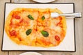 Roman pizza with cheese and tomatoes is taken from the plate with cutlery. Royalty Free Stock Photo
