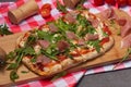 roman pizza with jamon and arugula on a wooden board