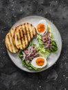 Roman salad boat with canned tuna and boiled egg - delicious breakfast, tapas, snack on a dark background, top view