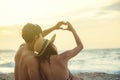 Romance couple made a heart shape together by hands on the beach at sunset. Love, wedding and valentine concept