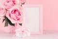 Romance festive interior - delicate pastel pink flowers, blank frame and gift box with gentle ribbon and bow on white wooden table Royalty Free Stock Photo