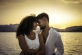 Romance scene of multiracial stylish couple in love looking in eyes head to head at sunset with sun setting among mountain in