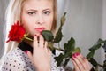 Woman holding red rose near face looking melancholic