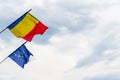 Romanian flag and European Union flag waving in high winds, with stormy clouds in the background, in Sibiu, Romania - copy space Royalty Free Stock Photo
