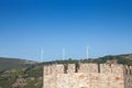 Romanian Wind Farm with Wind Turbine and windmills facing an old castle located on the Serbian side of the Danube river Royalty Free Stock Photo