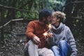 Romantic adult couple kissing in love holding fire sparklers sitting in the nature park enjoy outdoor relationship and leisure Royalty Free Stock Photo