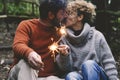 Romantic adult couple kissing in love holding fire sparklers sitting in the nature park enjoy outdoor relationship and leisure Royalty Free Stock Photo
