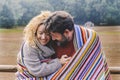 Romantic adult couple in love hug with tenderness under a colorful wool cover in outdoor park. Concept of winter leisure activity Royalty Free Stock Photo