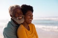 Romantic african american couple embracing and looking away while standing against sea and sky Royalty Free Stock Photo