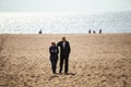 Romantic aged couple walking on beach at midday. Man hugs woman. Man and woman in love Royalty Free Stock Photo