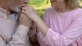 Romantic aged man kissing wife hand, outdoor date in park, happy relations