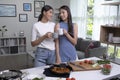 Romantic Asian lesbian couple is cooking on kitchen. LGBT lesbian couple are having fun together while preparing healthy food Royalty Free Stock Photo