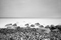 Romantic atmosphere in peaceful morning at sea. Big boulders sticking out from smooth wavy sea. Pink horizon Royalty Free Stock Photo