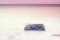 Romantic atmosphere in peaceful morning at sea. Big boulders sticking out from smooth wavy sea. Pink horizon Royalty Free Stock Photo