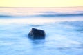 Romantic atmosphere in peaceful morning at sea. Big boulders sticking out from smooth wavy sea. Pink horizon Royalty Free Stock Photo