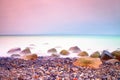 Romantic atmosphere in peaceful morning at sea. Big boulders sticking out from smooth wavy sea. Pink horizon Royalty Free Stock Photo