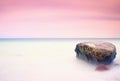 Romantic atmosphere in peaceful morning at sea. Big boulders sticking out from smooth wavy sea. Pink horizon Royalty Free Stock Photo