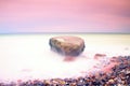 Romantic atmosphere in peaceful morning at sea. Big boulders sticking out from smooth wavy sea. Pink horizon Royalty Free Stock Photo