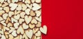 Romantic background of dozens of tiny wooden hearts with a single heart on a red card. For love, romance, or Valentine`s Day. Wit