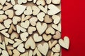 Romantic background of dozens of tiny wooden hearts with a single heart on a red card. For love, romance, or Valentine`s Day