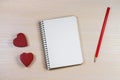 The romantic background with notepad, pencil and two red hearts.