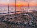 Romantic Beach Sunset with Two Swings in a Heart of Shells Royalty Free Stock Photo
