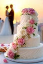 Romantic beach wedding with elegant three-tier rose cake at sunset Royalty Free Stock Photo