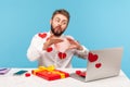 Romantic bearded man sending air kisses talking via web camera with girlfriend sitting at workplace all covered with sticky hearts Royalty Free Stock Photo