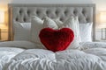 Romantic Bedroom Arrangement: A heart-shaped pillow nestled between white pillows on a simple bed, creating a romantic Royalty Free Stock Photo