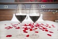 Romantic bedroom - glasses of red wine and rose petals on a bed Royalty Free Stock Photo