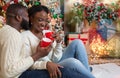 Romantic afro couple celebrating Christmas with hot winter cocoa
