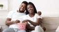 Romantic black couple eating popcorn and watching movie at home together