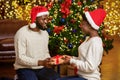 Romantic black couple exchanging presents near Christmas tree