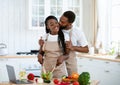 Romantic Black Couple Kissing While Cooking Healthy Food Together In Kitchen Royalty Free Stock Photo