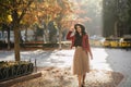 Romantic black-haired girl in long lush skirt enjoying sunshine in autumn park. Outdoor portrait of shy brunette female Royalty Free Stock Photo