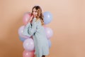 Romantic blonde girl looking over shoulder while posing with party balloons. Indoor photo of adorable young woman Royalty Free Stock Photo