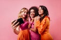 Romantic blonde girl making selfie with friends. Pretty ladies posing on pink background