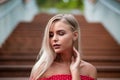Romantic blonde girl with naked shoulders wearing red dress, posing on the wooden staircase Royalty Free Stock Photo