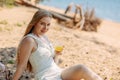 Romantic blonde woman in straw hat having picnic on sea beach. Fresh fruits, juice, cookies and peaches Royalty Free Stock Photo