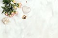 Romantic border of rose flowers, gift box and decorative hearts on white fur background. Place for text, top down composition Royalty Free Stock Photo