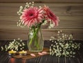 A romantic bouquet of pink gerberas in a glass vase. Gypsophila flowers and candles as decor