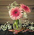 A romantic bouquet of pink gerberas in a glass vase. Gypsophila flowers, flower petals and envelopes